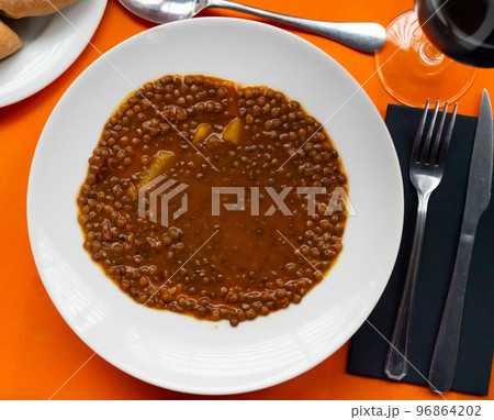 Stewed lentils with suasage and vegetables with thick tomato sauce. Spanish cuisine Stewed lentils with suasage and vegetables with thick tomato sauce. Spanish cuisine 96864202