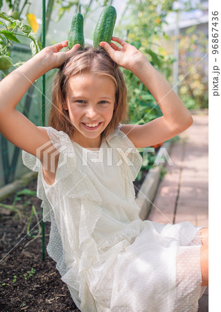 Adorable girl having fun in greenhouse. Portrait of kid with basket with vegetables 96867436