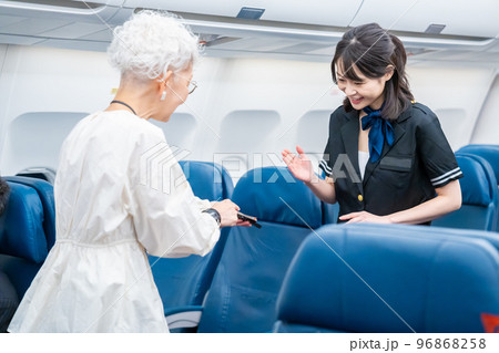 高齢の乗客を案内するキャビンアテンダント 96868258
