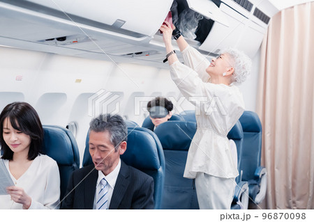 機内持ち込みの荷物を取り出す乗客 機内持ち込みの荷物を取り出す乗客 96870098