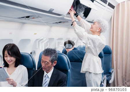 機内持ち込みの荷物を取り出す乗客 機内持ち込みの荷物を取り出す乗客 96870103