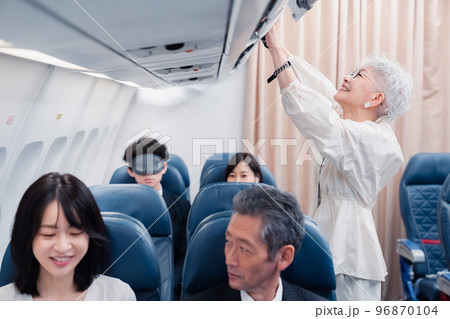 機内持ち込みの荷物を取り出す乗客 機内持ち込みの荷物を取り出す乗客 96870104