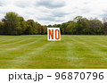 何もない広い草原の真ん中に立つ「NO」と書かれた大きな看板。 96870796