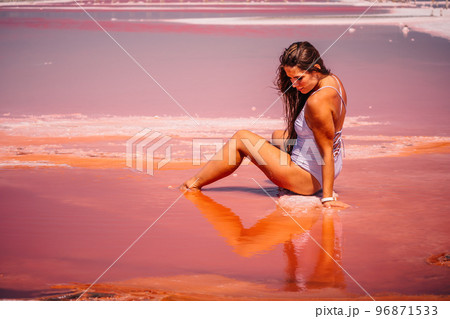 Young woman with long hair in pink salty lake with crystals of salt. Extremely salty pink lake, colored by microalgae with crystalline salt depositions. Spa, beauty and health care concept. 96871533