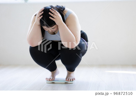 体重計に乗って頭を抱える女性 96872510