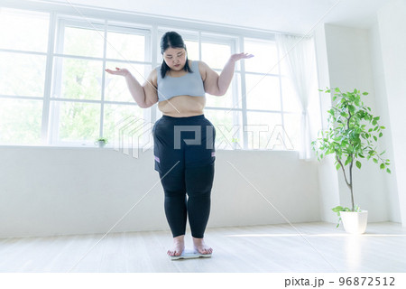 体重計に乗って肩をすくめる女性 96872512