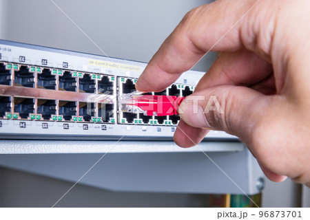 hand of administrator plugging in red patch cable into empty switchboard hand of administrator plugging in red patch cable into empty switchboard 96873701