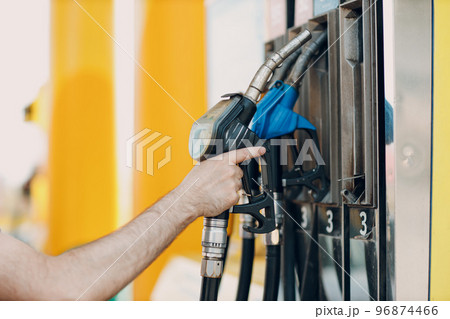 Man holding filling gun in his hand at gas station. Man holding filling gun in his hand at gas station. 96874466