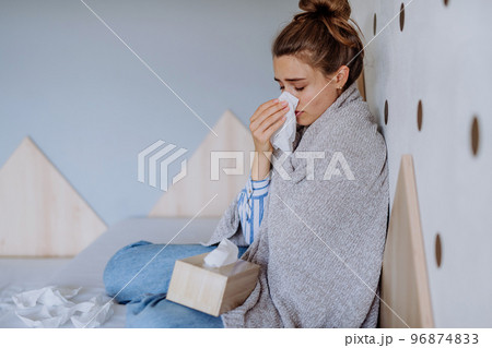 Sick woman sitting in bed, having a cold. Sick woman sitting in bed, having a cold. 96874833