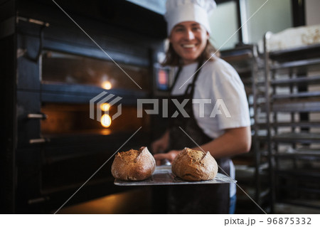 Happy young baker with fresh bread, in bakery. Happy young baker with fresh bread, in bakery. 96875332