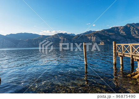 Wooden Pier on the Coast of Lake Garda - Malcesine Village Veneto Italy Wooden Pier on the Coast of Lake Garda - Malcesine Village Veneto Italy 96875490