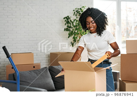 Happy african young woman with cardboard box moving to a new place Happy african young woman with cardboard box moving to a new place 96876941