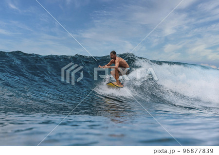 Shirtless male surfer on a wave at sunny day Shirtless male surfer on a wave at sunny day 96877839