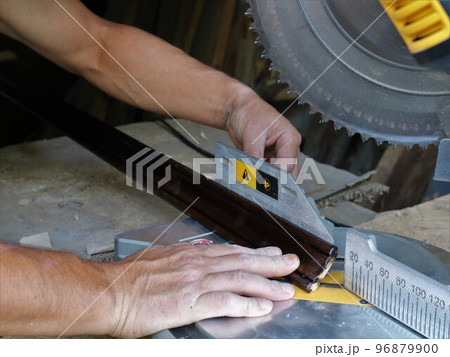adjusting the size when cutting a wooden plinth on the base of a miter saw, working with a wooden material on a circular saw in a carpenter's workshop, trimming the edge of a wooden fillet 96879900
