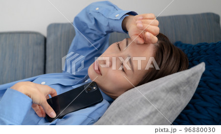 スマートフォンを持ちながら寝てしまう女性 96880030