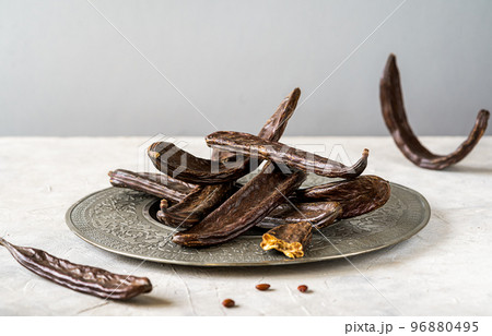 Carob pods group on grey antique plate with light grey background and copy space for text Carob pods group on grey antique plate with light grey background and copy space for text 96880495