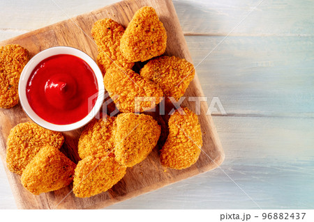 Chicken nuggets with ketchup sauce on a rustic wooden background Chicken nuggets with ketchup sauce on a rustic wooden background 96882437