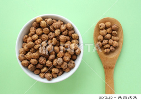Chufa, tigernut, earth almond on white ceramic bowl and wooden spoon on green background. Healthy vegan food concept. Tiger nut for flour, oil, milk, traditional typical drink horchata Valencia Spain Chufa, tigernut, earth almond on white ceramic bowl and wooden spoon on green background. Healthy vegan food concept. Tiger nut for flour, oil, milk, traditional typical drink horchata Valencia Spain 96883006