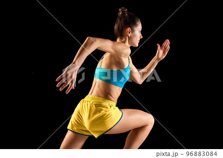 Young sportive woman, runner and jogger in motion action isolated on black background. Sport, fitness, energy, movements concept Young sportive woman, runner and jogger in motion action isolated on black background. Sport, fitness, energy, movements concept 96883084
