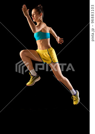 One sportive girl in sports uniform jumping high isolated over black background. Concept of sport, beauty, action, achievements, hobbies One sportive girl in sports uniform jumping high isolated over black background. Concept of sport, beauty, action, achievements, hobbies 96883103
