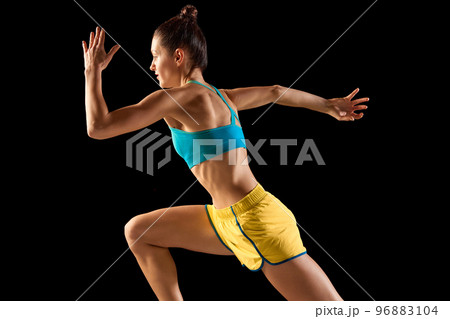 Young sportive woman, runner and jogger in motion action isolated on black background. Sport, fitness, energy, movements concept 96883104