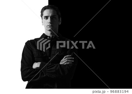 Black and white portrait of young man in casual shirt posing, seriously, attentively looking at camera. Businessman. Concept of men's fashion, business, emotions Black and white portrait of young man in casual shirt posing, seriously, attentively looking at camera. Businessman. Concept of men's fashion, business, emotions 96883194
