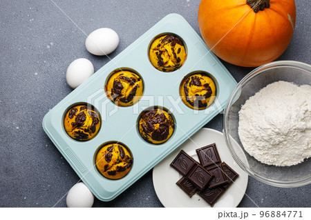 Pumpkin muffins baked in the silicone mold at the table with ingredients. Pumpkin muffins baked in the silicone mold at the table with ingredients. 96884771