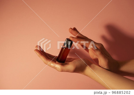 Brown bottle in beautiful hands on a peachy light background. 96885202