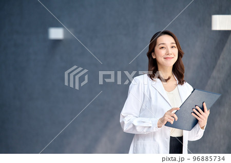 病院でカルテを確認する白衣を着た笑顔の女性医師 病院でカルテを確認する白衣を着た笑顔の女性医師 96885734