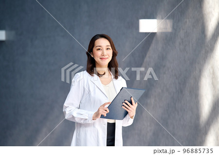 病院でカルテを確認する白衣を着た笑顔の女性医師 96885735