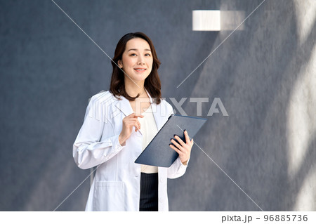 病院でカルテを確認する白衣を着た笑顔の女性医師 96885736