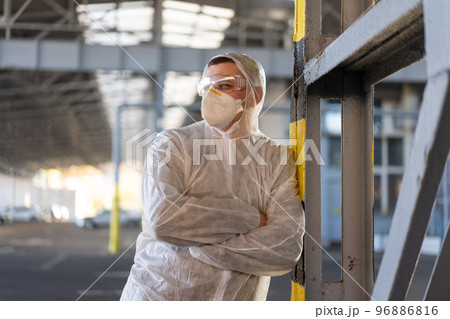 COVID-19 coronavirus doctor standing hospital parking dressed white protective overalls hazmat suit. COVID-19 coronavirus doctor standing hospital parking dressed white protective overalls hazmat suit. 96886816