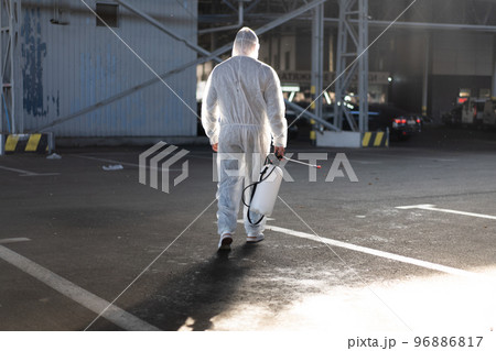 Man dressed white protective overalls spraying surface antibacterial sanitizer sprayer during quarantine Man dressed white protective overalls spraying surface antibacterial sanitizer sprayer during quarantine 96886817