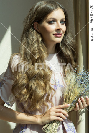 Portrait of a gorgeous woman with curly hair. The girl holds a bouquet of lavender in her hands and looks directly into the camera. High quality photo Portrait of a gorgeous woman with curly hair. The girl holds a bouquet of lavender in her hands and looks directly into the camera. High quality photo 96887520