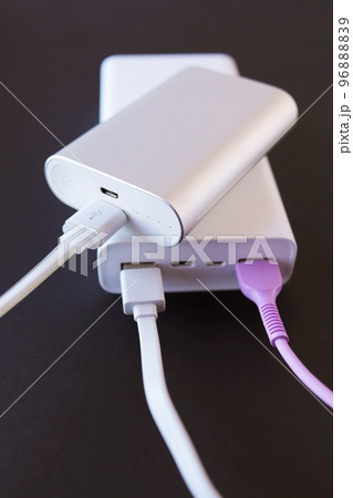 Power bank, external battery and usb wire on the table, universal mobile battery for charging gadgets, for recharging a smartphone 96888839