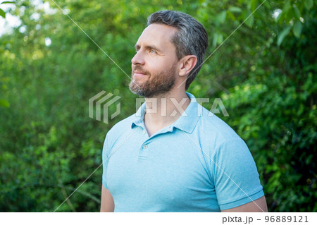 Portrait of handsome guy in blue tshirt looking aside natural background 96889121