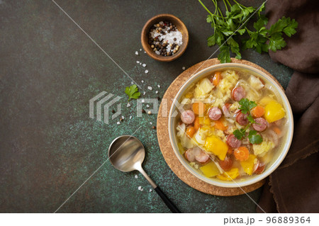 Traditional Zelnacka cabbage soup with sausages and vegetables in a bowl on a stone tabletop. Czech cuisine. View from above. Copy space. 96889364
