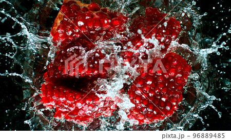 Fresh pomegranate falling into water, black background 96889485