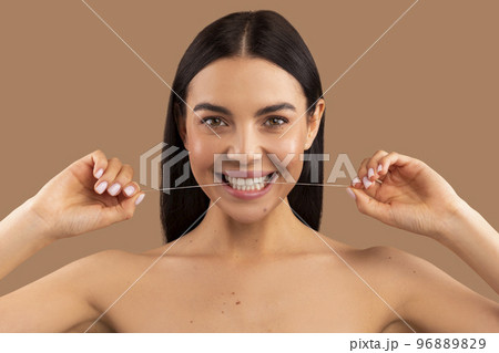 Headshot of beautiful cheerful naked woman using dental thread Headshot of beautiful cheerful naked woman using dental thread 96889829