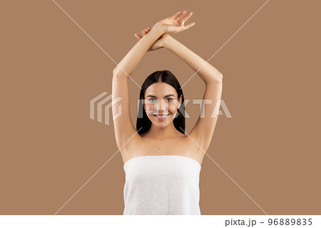 Beautiful half-naked woman with hands up posing on beige 96889835
