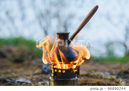 Cooking coffee in cezve on portable wood burner 96890244