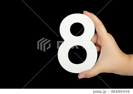 Number eight in hand isolated on black background. Number 8 in a child's hand on a black background. To be inserted into a project or design. 96890456