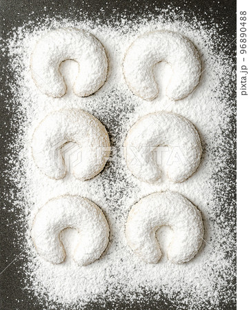 With vanilla sugar heavy dusted vanilla crescents, Vanillekipferl on a baking tray. Crescent shaped Christmas biscuits, originally from Austria, made with walnuts, butter, flour and vanilla sugar. 96890488