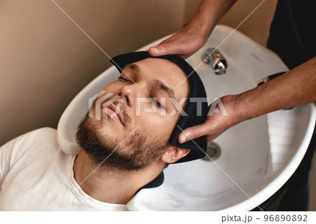 Barber washing hair of caucasian man , close-up Barber washing hair of caucasian man , close-up 96890892