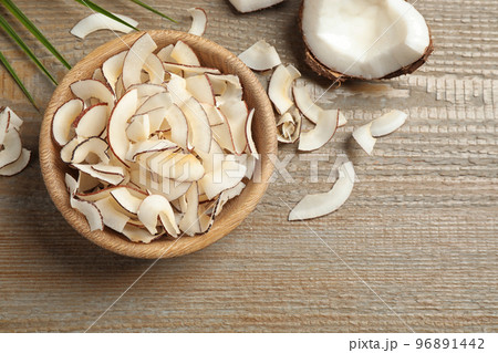 Tasty coconut chips on wooden table, flat lay Tasty coconut chips on wooden table, flat lay 96891442
