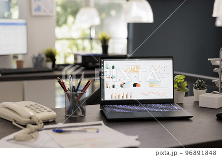 Portable computer with main management program on screen on modern office desk. Laptop display statistics and financial results with profit and investment reports, inside workplace. Portable computer with main management program on screen on modern office desk. Laptop display statistics and financial results with profit and investment reports, inside workplace. 96891848