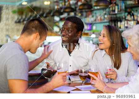 Happy diverse people drinking beer and eating tapas while spending time together in a bar 96893961