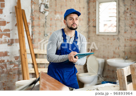 Foreman making task list during works in building under construction Foreman making task list during works in building under construction 96893964
