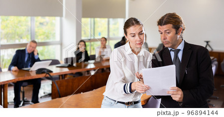Secretary and employer discussing documentation during business meeting 96894144