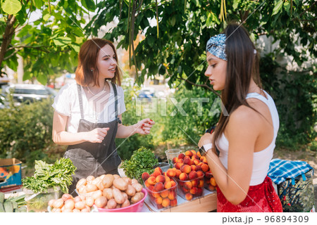 Seller woman offers fresh and organic vegetables farmers market. 96894309